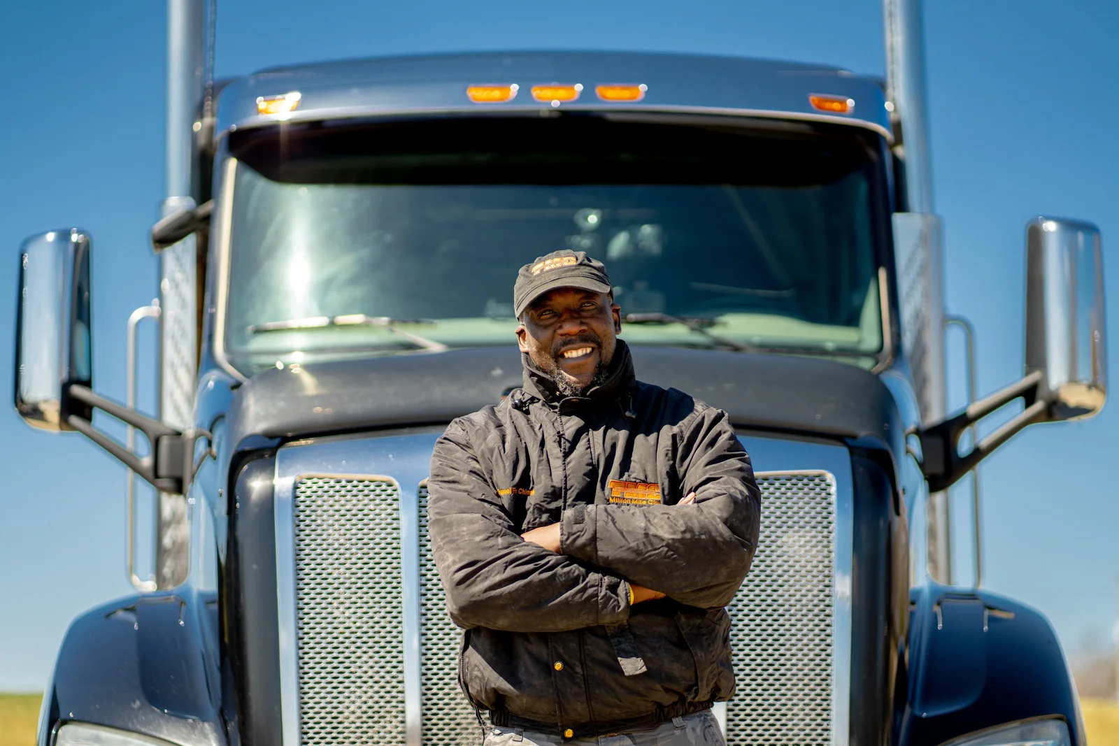 Professional driver standing in front of a blue commercial truck