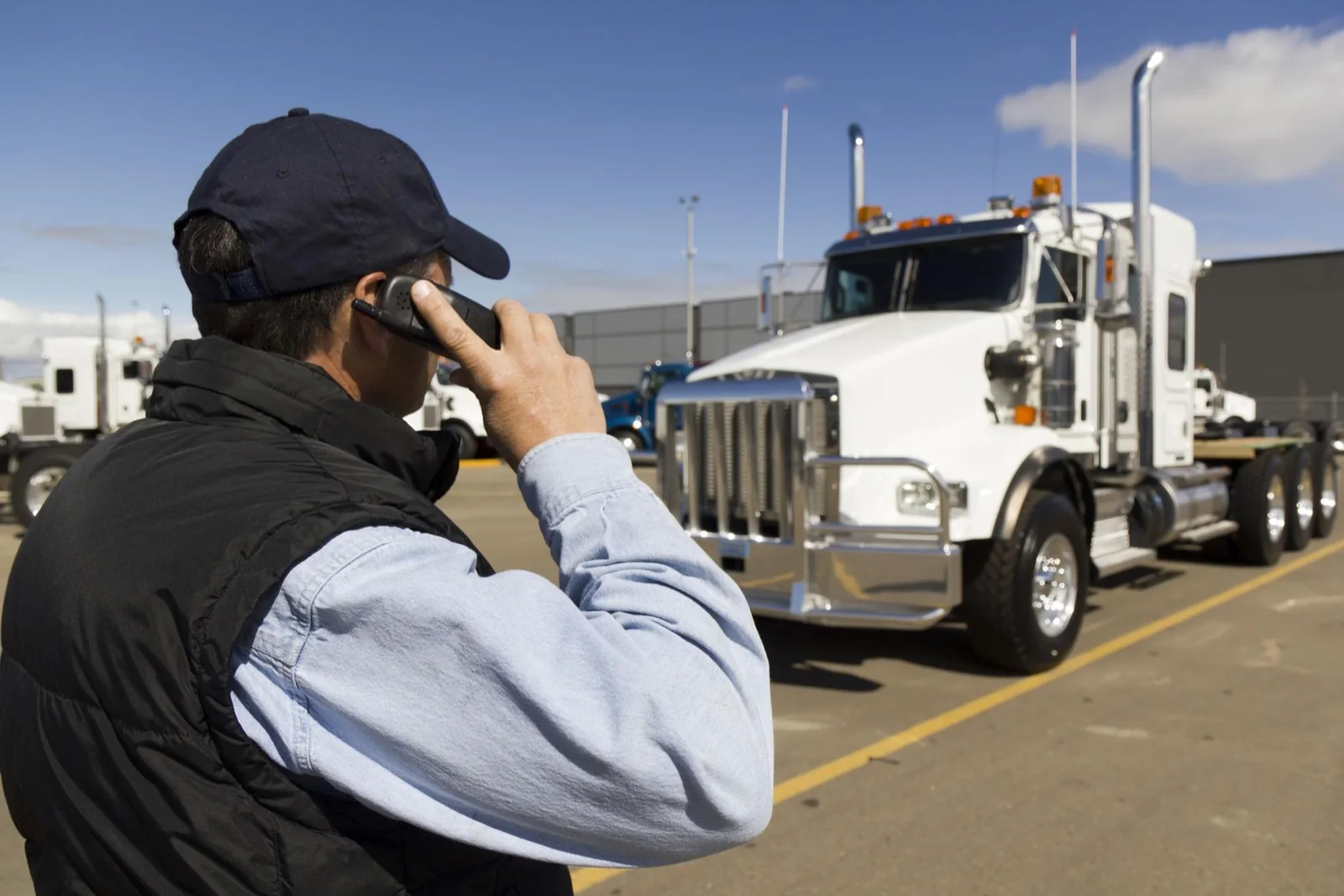 Professional driver speaking by phone beside a commercial truck