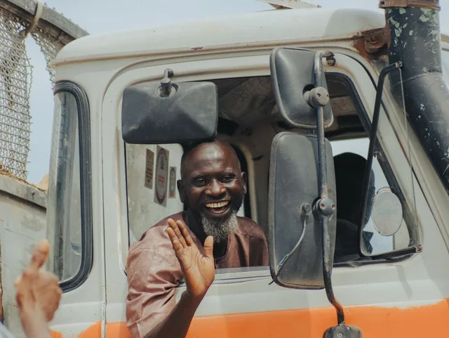 Smiling truck driver waving from the cab window