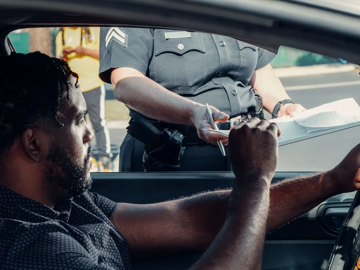 Driver receiving traffic-stop paperwork from a police officer