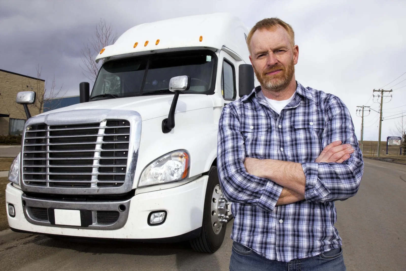 Professional truck driver standing in front of a white commercial truck