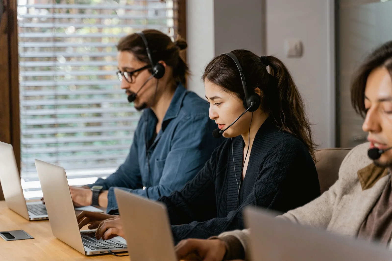 Customer support agents wearing headsets and working on laptops